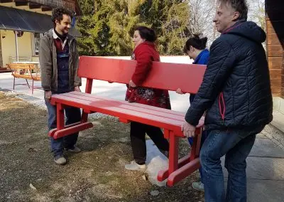 Volunteers and Rafa Lobsang Dorje carry a red-painted bench during KALAPA CARE, the volunteer week at Kalapa Retreat Center.